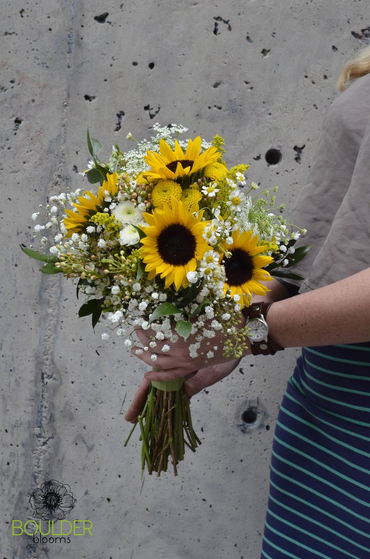 a woman holding a bouquet of sunflowers and baby's breath