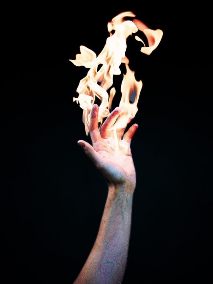 a hand holding fire in the air with it's fingers extended out to catch something