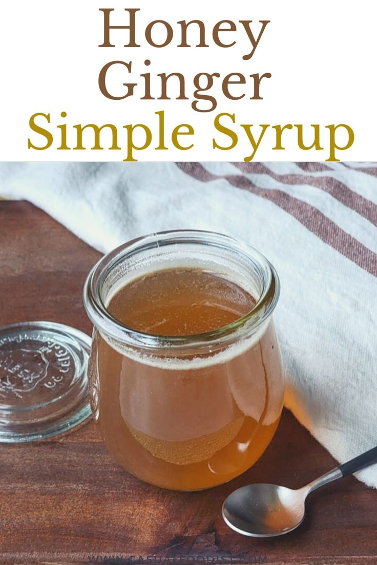 a glass jar filled with honey sitting on top of a wooden table next to a spoon