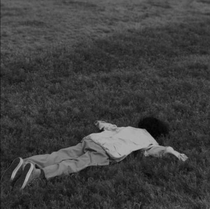 a person laying in the grass with their head on his back and one foot up