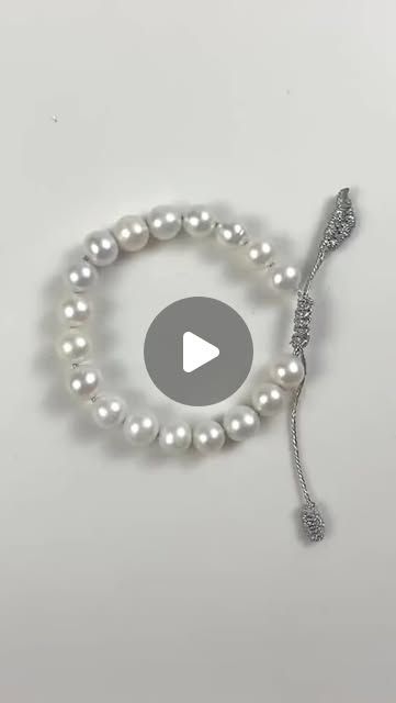 a white bracelet with pearls and a silver beaded charm on the end of it