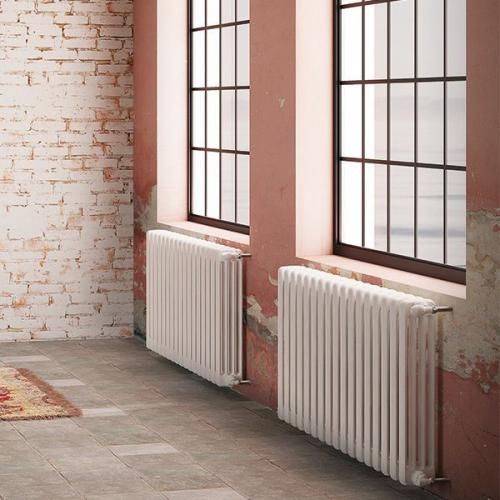 an empty room with two windows and a radiator in the corner, next to a brick wall