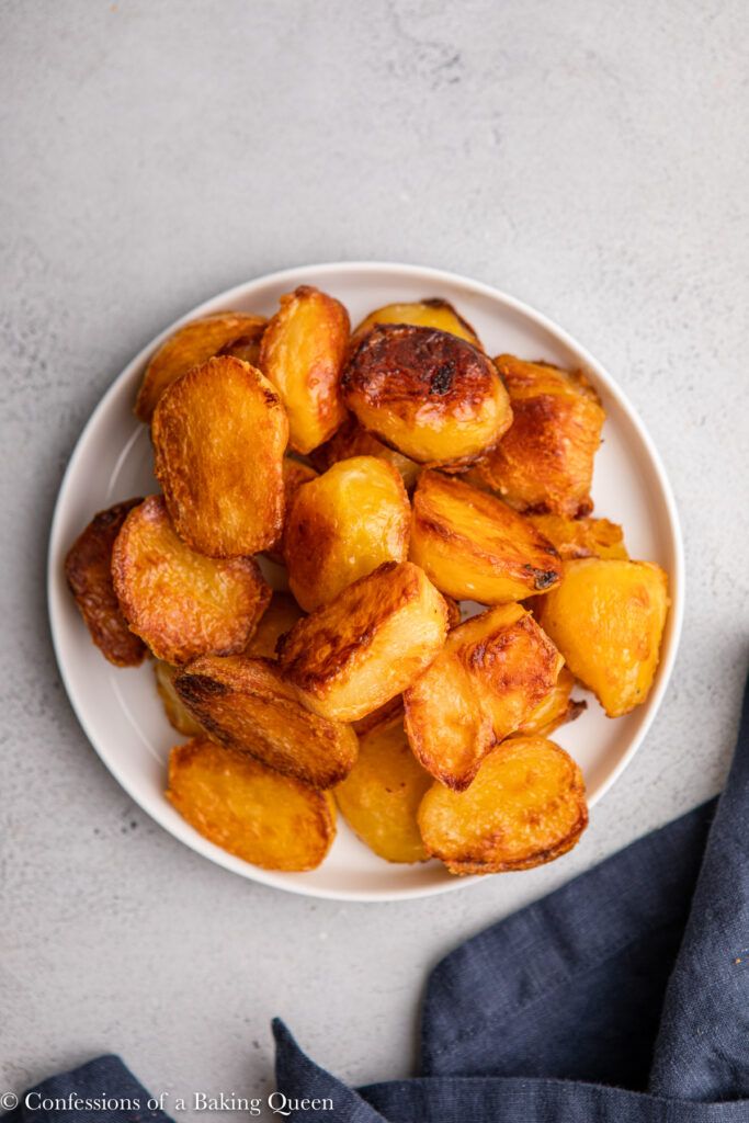 a white plate topped with roast potatoes on top of a table