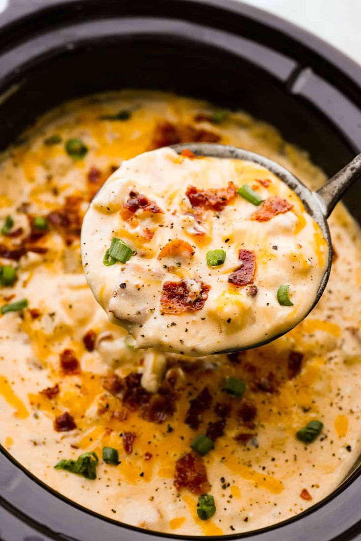 a ladle full of cheese and bacon dip in a slow cooker with a spoon