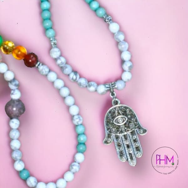 Welcome the Hamsa Chakra Healing Mala into your life! Be blessed with protection and equipped for healing with this beautiful 108 mala bead. With seven chakra stones and Amazonite, Howlite, and Turquoise accent stones all made of crystal, your spiritual security is guaranteed! The addition of Amethyst makes this piece especially powerful, - purifying your aura by removing any negative energy or feelings while grounding you in its powerful calming energy.But it doesn't stop there! This incredible Silver Beaded Spiritual Mala, Spiritual Amazonite 8mm Beads Jewelry, Spiritual Amazonite Beaded Necklace For Healing, Spiritual Amazonite Jewelry With 8mm Beads, Spiritual Amazonite Crystal Necklace With Gemstone Beads, Spiritual Silver Mala With 8mm Beads, Spiritual Agate Mala With 108 Beads, Silver Spiritual Mala For Meditation, Spiritual Silver Mala For Meditation