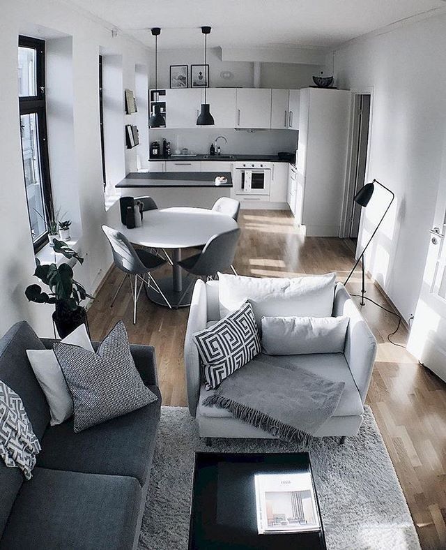 a living room filled with furniture next to a kitchen and dining room table on top of a hard wood floor