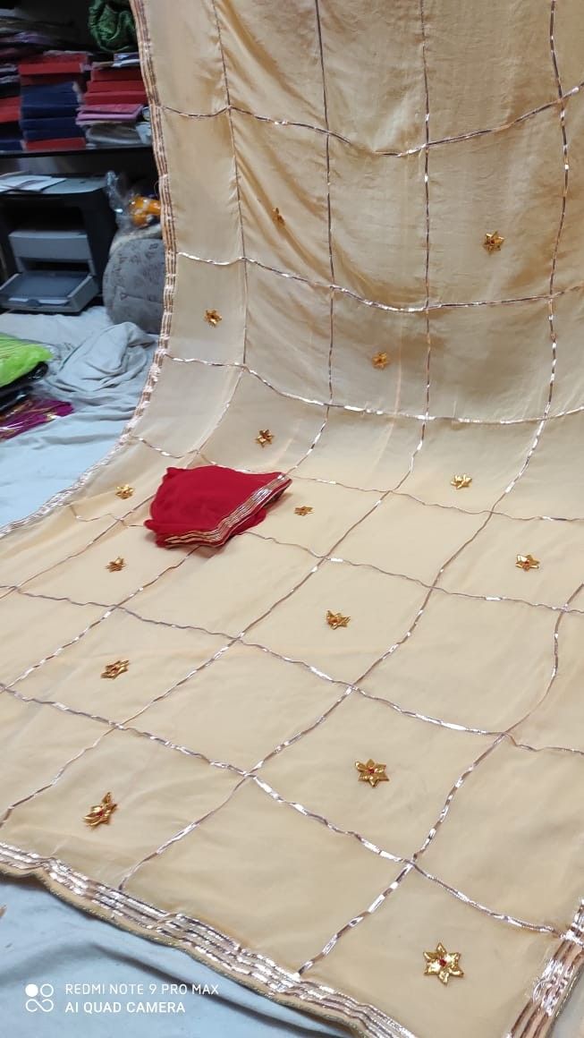 a red piece of cloth sitting on top of a bed covered in gold stars and sequins