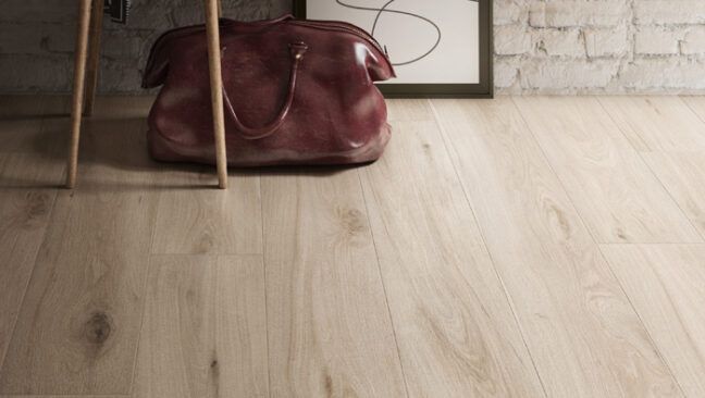 a brown purse sitting on top of a wooden floor next to a white brick wall