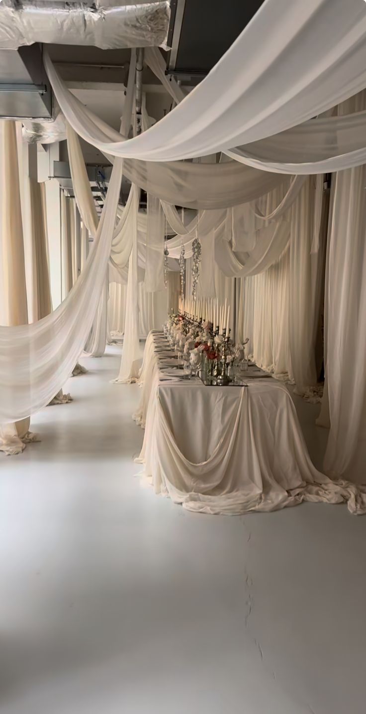 a room filled with lots of white drapes and tables covered in cloth draped over them