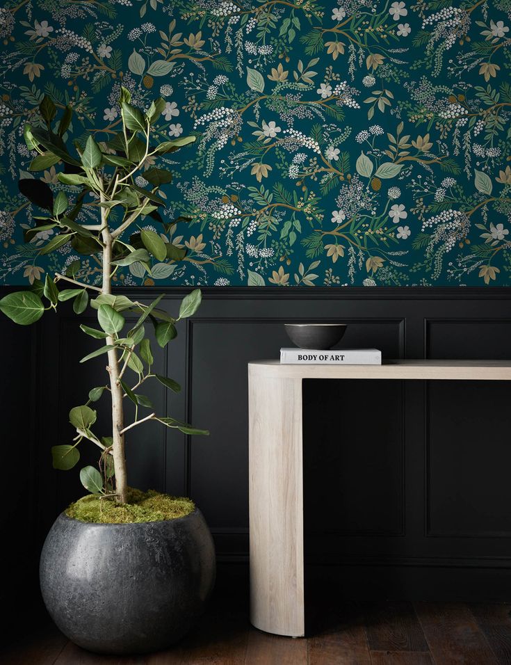 a potted plant sitting on top of a table next to a wallpapered wall