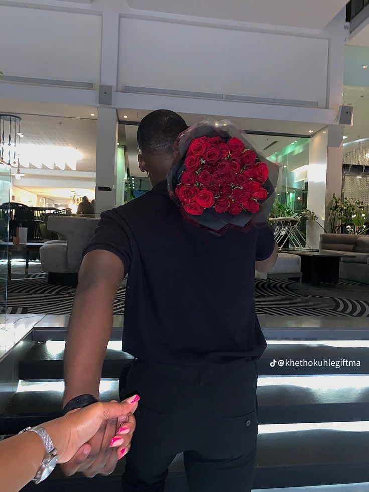 a woman is holding a bouquet of red roses in her hand while another person looks on