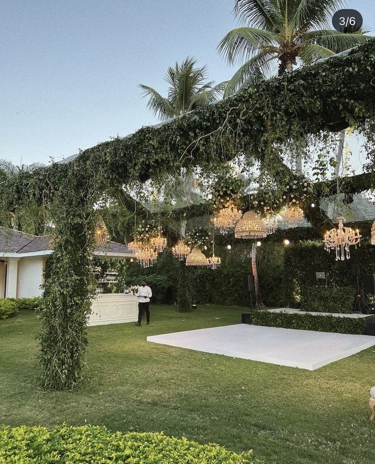 a man standing in the middle of a lush green yard next to a white dance floor