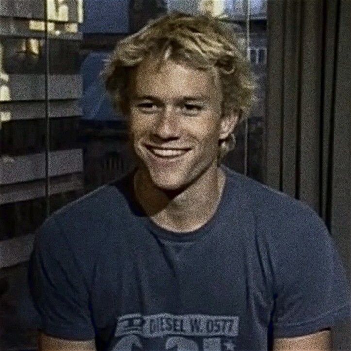 a young man smiling in front of a window