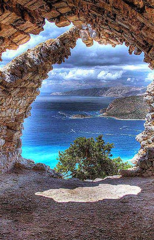 an image of a view from the top of a rock arch with water and land in the background