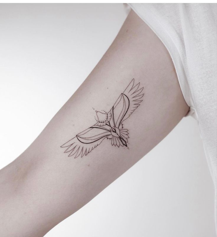 a tattoo on the arm of a woman with a bird flying above her left arm