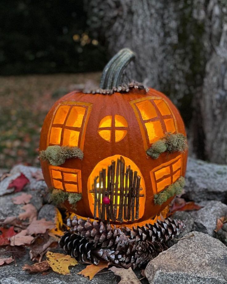 a pumpkin shaped like a house sitting on top of some rocks