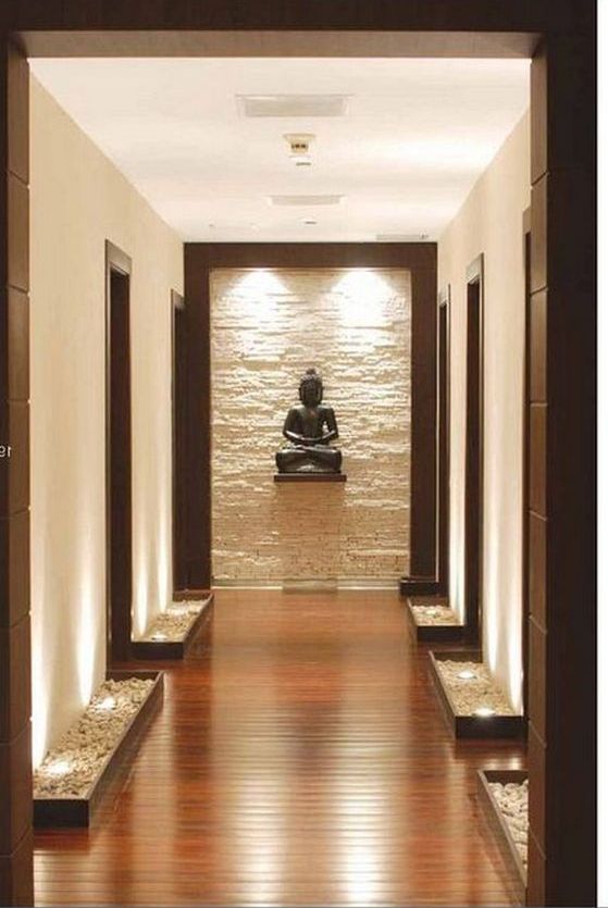 a long hallway leading to a buddha statue in the center with lights on either side