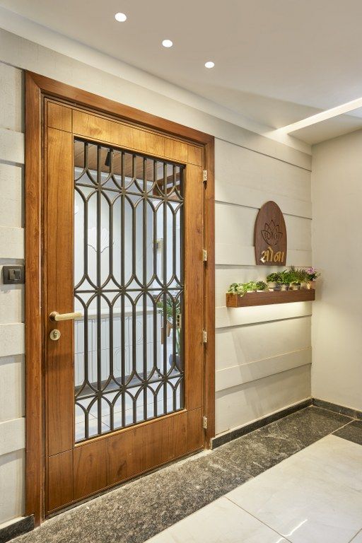 a wooden door with iron bars on the front and side panels, in a white room