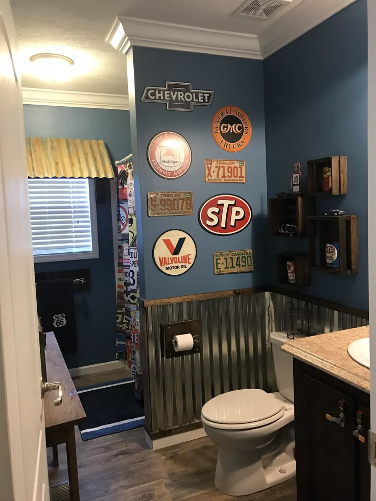 a bathroom with blue walls and various signs on the wall above the toilet, along with a sink