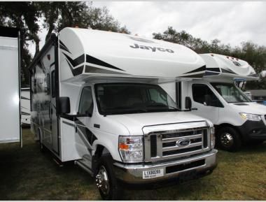 two white trucks parked next to each other in a grassy area with trees and bushes