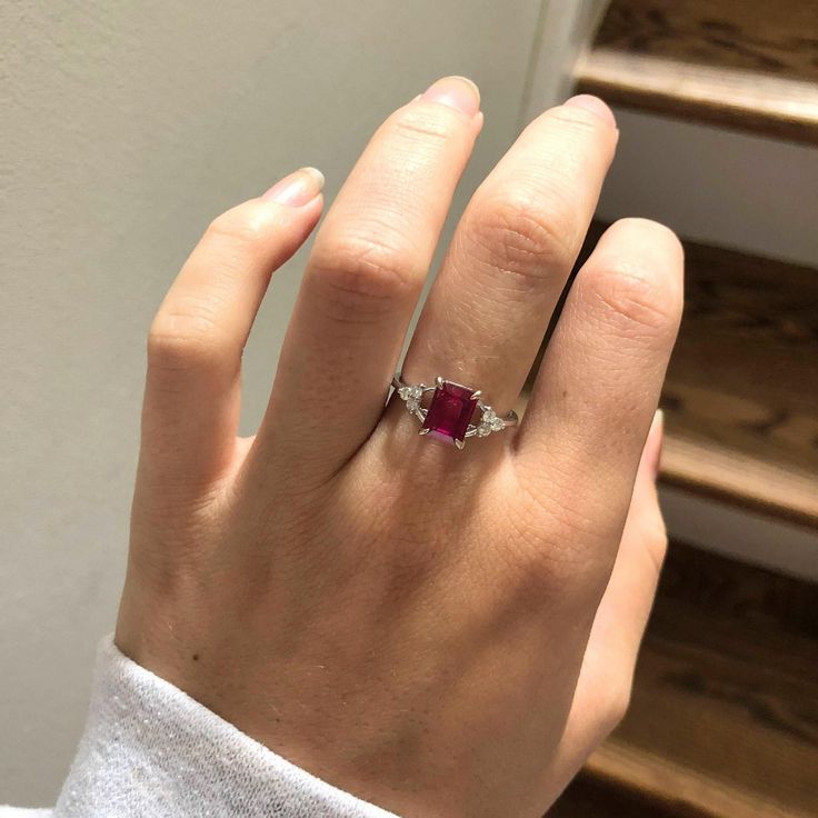 a woman's hand with a diamond and ruby ring on top of her finger