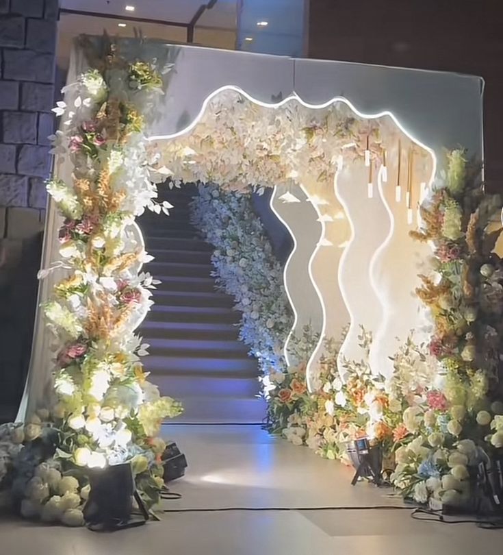 an entrance decorated with white flowers and greenery for a formal function or wedding ceremony