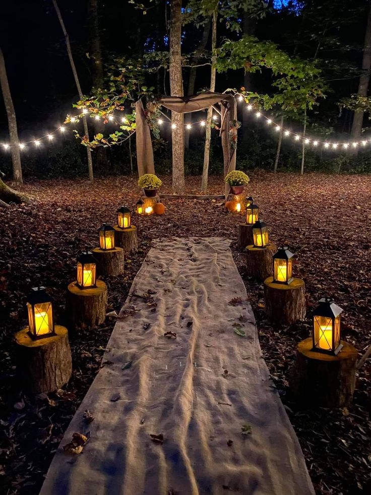 a wooden table topped with lots of lights next to a forest filled with trees and leaves