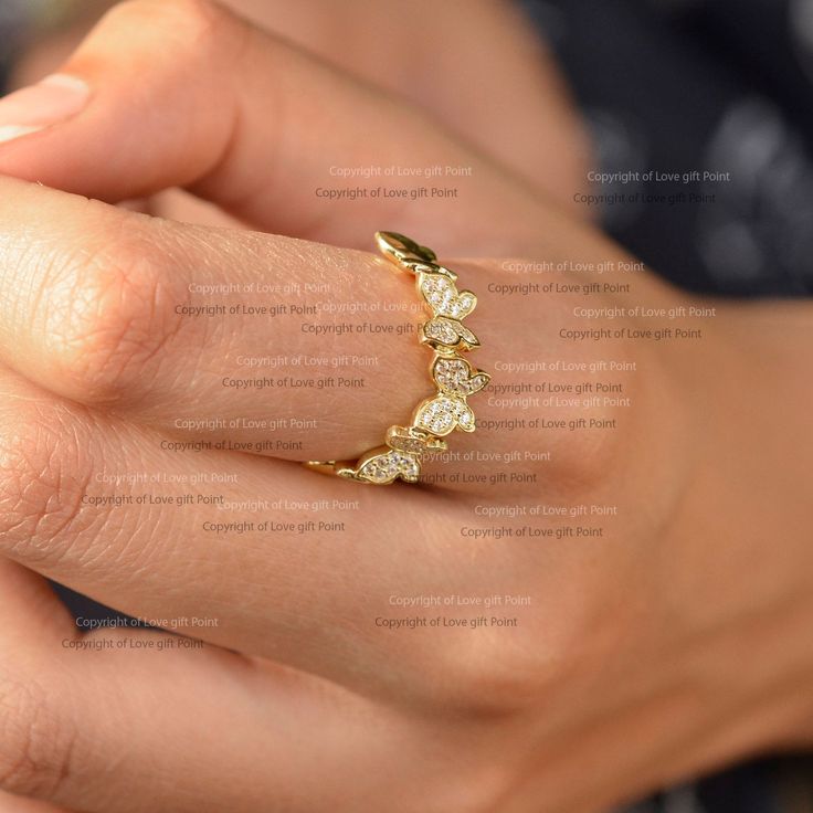 a woman's hand holding a gold ring with five small white diamonds on it