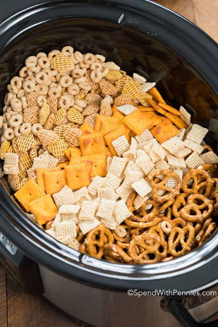 a crock pot filled with cheetos and pretzels for snacking