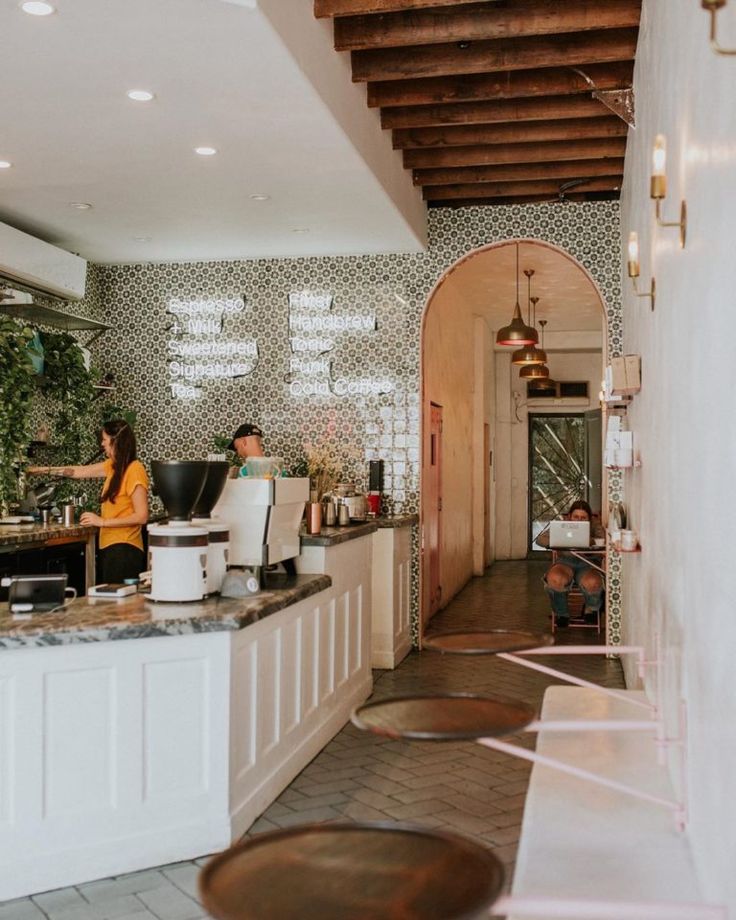 two women sitting at a counter in a restaurant with tiled walls and wood beams on the ceiling