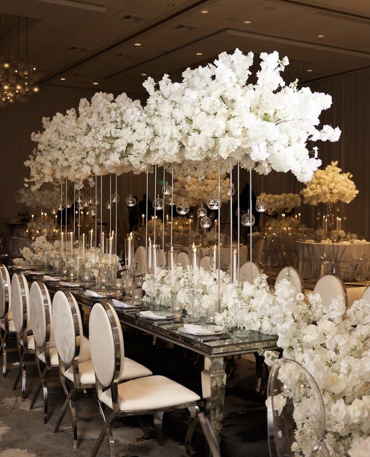 a long table with white flowers and candles on it is set for an elegant dinner