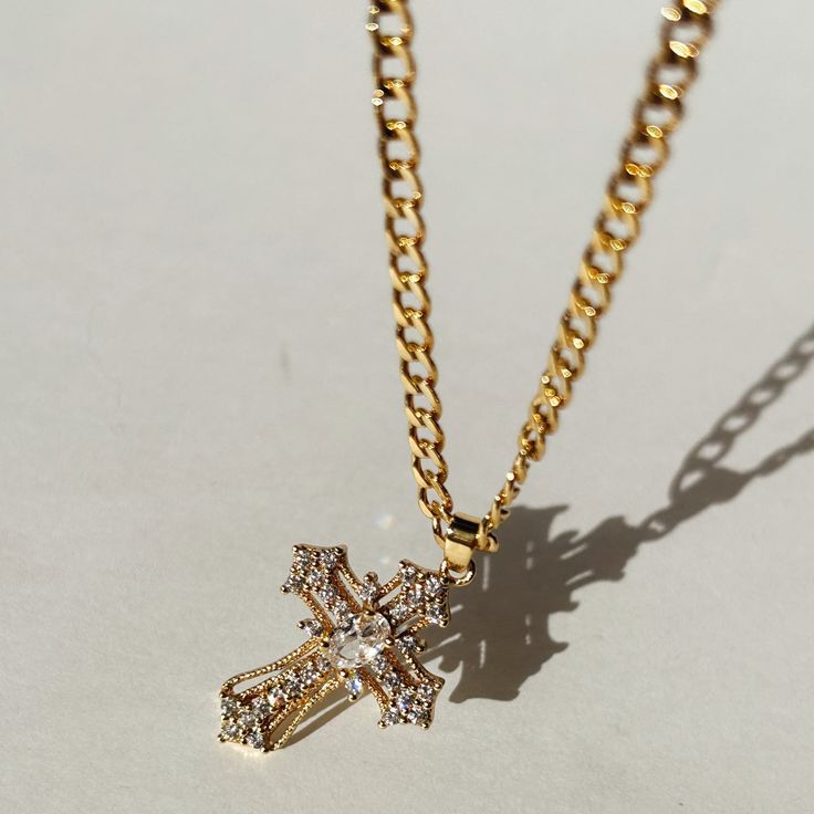 Our Miraculous Cross Necklace is the perfect symbol of faith and elegance. The cross pendant hangs on a stylish 14K Gold Filled curb chain. The Miraculous Cross Necklace is perfect for that statement piece you are looking to add to your collection.  Product Details 16" 3.5mm 14k Gold-Filled Curb Chain with 2" Extender Gold Cross Necklace With Diamond, Gold Plated Cross Chain Necklace, 14k Gold Cross Necklace With Adjustable Chain, Cross Pendant Chain Necklace, Adjustable Gold Plated Cross Pendant Necklace, Adjustable Chain Cross Pendant Necklace, Gold Plated Cross Pendant Necklace With Adjustable Chain, Gold Plated Chain Necklace With Cross Pendant, Gold Plated Cross Pendant Necklace