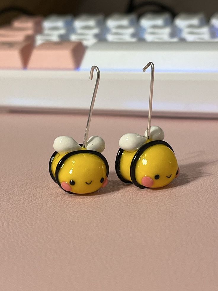 small yellow and black bee earrings on pink surface