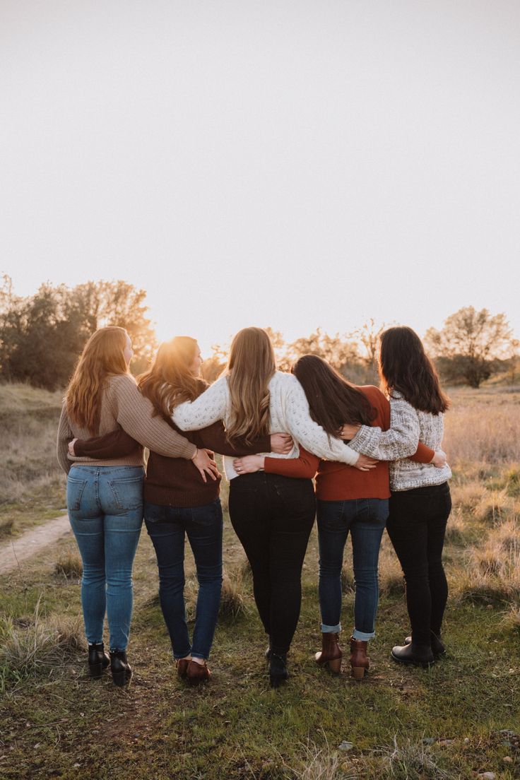 four girls standing in a circle with their arms around each other looking at the sky