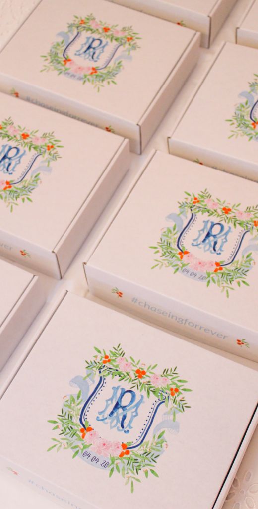 six personalized wedding boxes with monogrammed initials and flowers on the front, sitting on a table