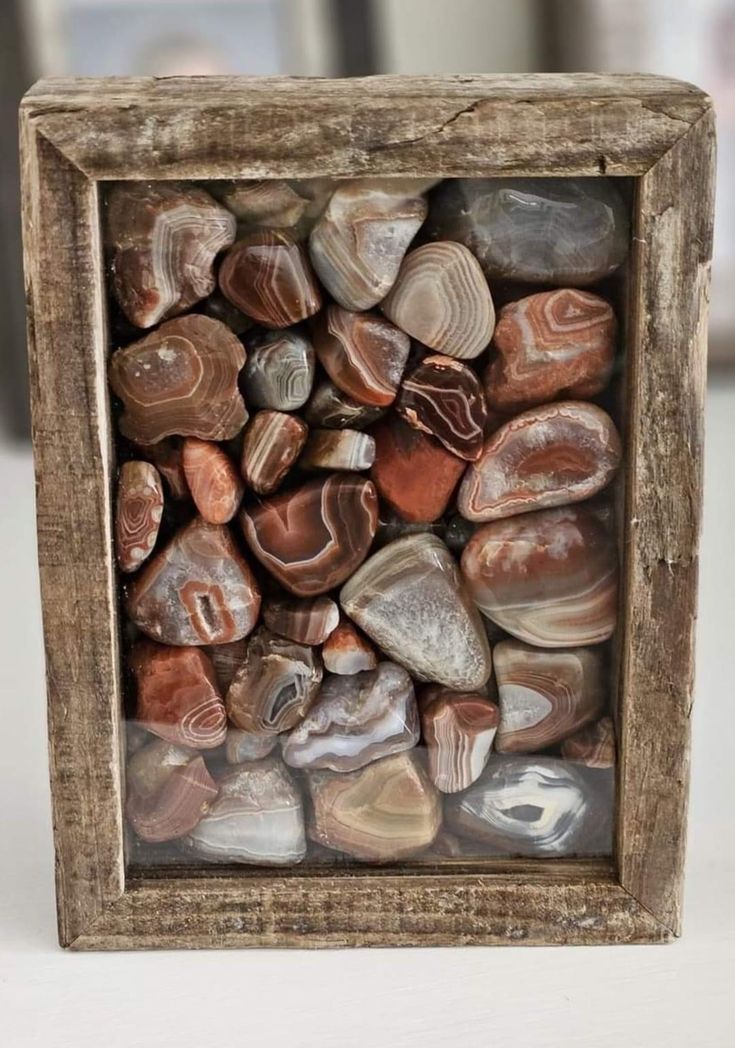 a wooden frame filled with lots of different colored rocks and stones on top of each other