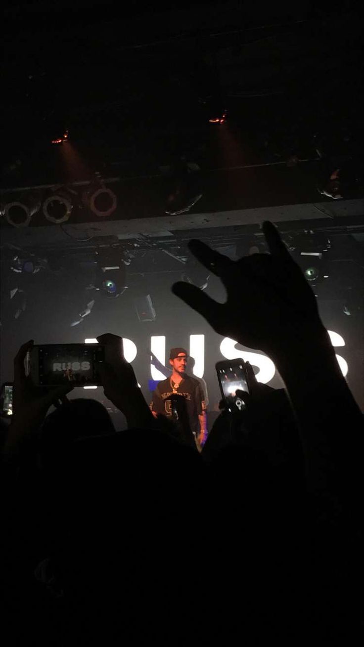 a man standing on top of a stage holding his hands up in front of him