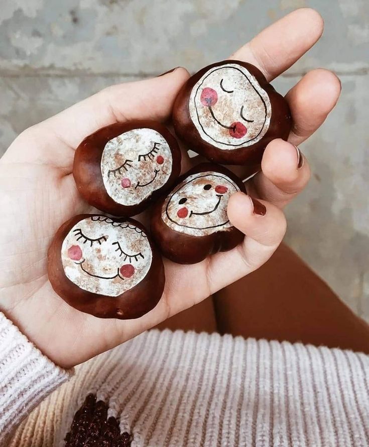 a person holding four chocolates with faces painted on them