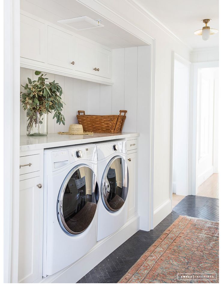 a washer and dryer in a white laundry room with an area rug on the floor