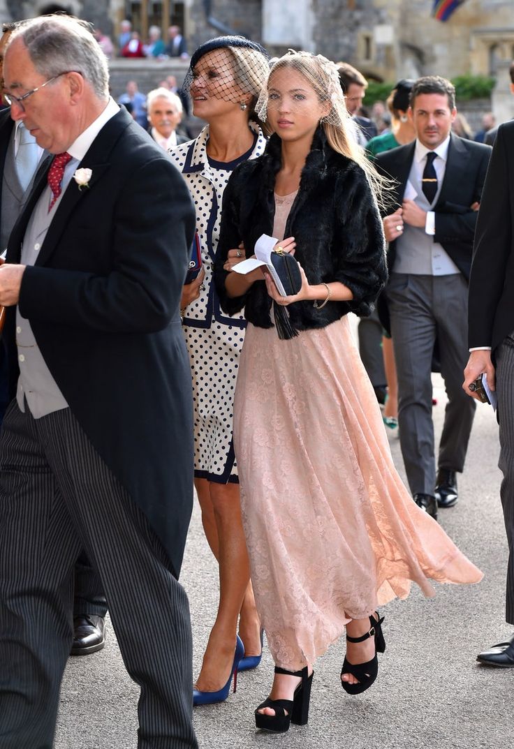 people are walking down the street in suits and ties, one woman is wearing a pink dress