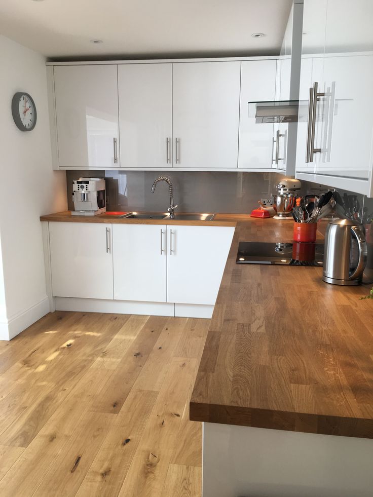 a kitchen with white cabinets and wooden counter tops in front of a clock on the wall