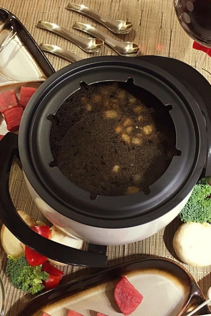 a pot filled with food sitting on top of a table next to utensils