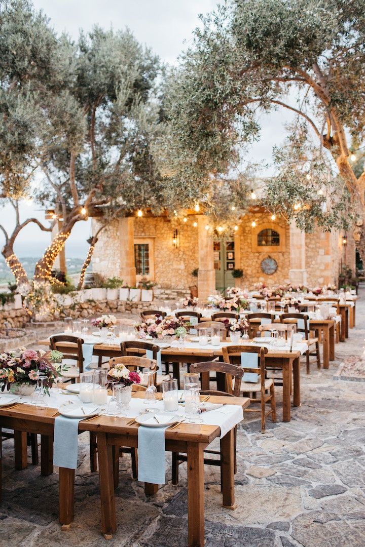 an outdoor dining area with wooden tables and white tablecloths, surrounded by trees