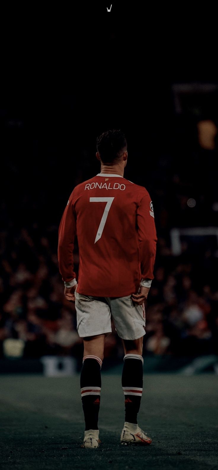 a man standing on top of a soccer field wearing a red shirt and white shorts