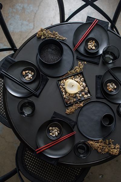 a black table topped with lots of plates and bowls