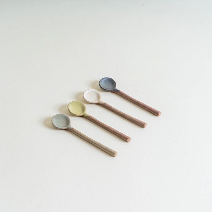 five spoons are lined up on a white surface