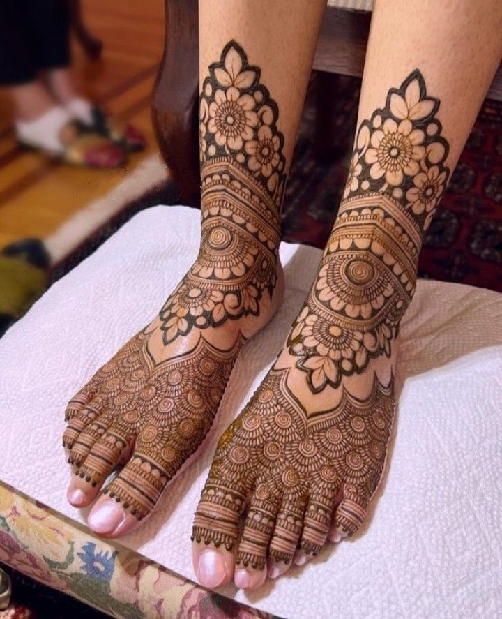 the feet and hands of a woman with henna tattoos