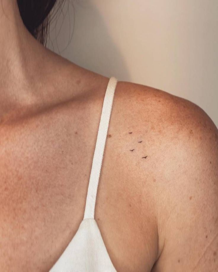 the back of a woman's shoulder with small black dots on it