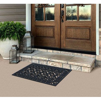 a door mat on the front steps of a house with potted plants next to it