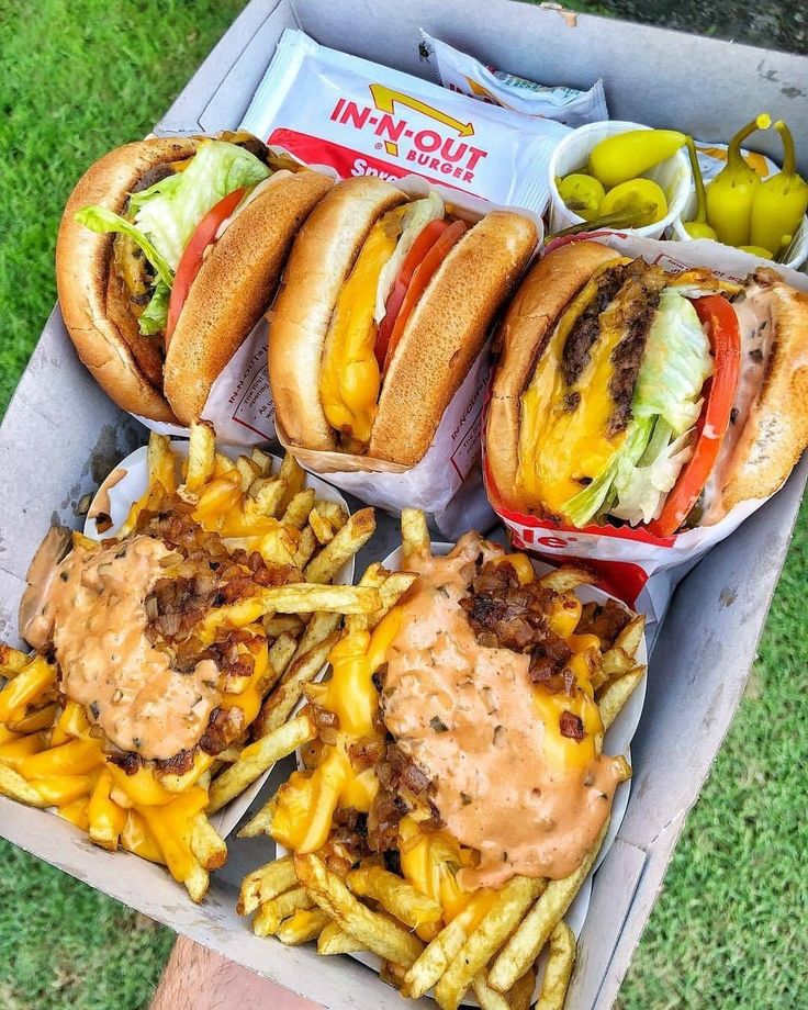 several sandwiches and fries are sitting on a picnic table